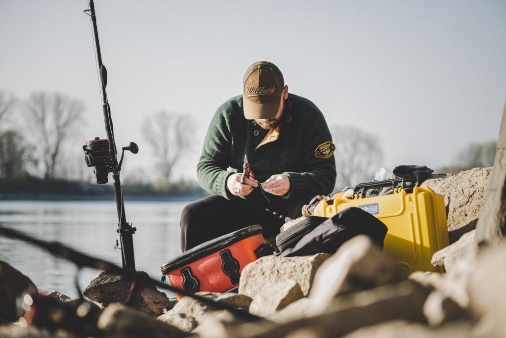 Angler mit wasserdichten Hartschalenkoffern und Angel am See